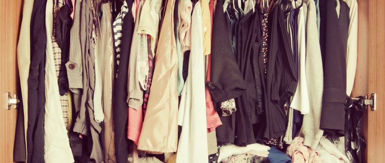 Pile of messy clothes in closet. Untidy cluttered woman wardrobe in vintage style.