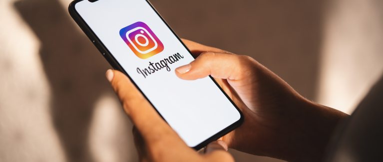 BERLIN, GERMANY JULY 2019: Woman hand holding iphone Xs with logo of instagram application. Instagram is largest and most popular photograph social networking.